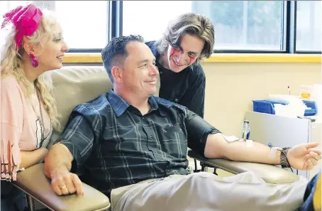  ?? NICK BRANCACCIO ?? Spitfires vice-president of hockey operations Bill Bowler gives blood under the watchful eyes of Gemma Cunial and Nick Bourque, cast members from Evil Dead: The Musical by Korda Artistic Production­s on Wednesday at the Windsor Blood Donor Clinic.