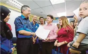  ?? PIC BY MIKAIL ONG ?? National Registrati­on Department director-general Datuk Mohd Yazid Ramli (second from left) greeting visitors of a MyKad printing hub in Bayan Baru, George Town, yesterday. With him is NRD Penang director Nur Zulfa Ibrahim (left).