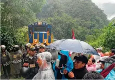  ?? — AFP photo ?? Tour operators and residents demonstrat­e against the opening of online ticket sales to the Inca citadel as policemen secure the rail tracks near Machu Picchu Pueblo.