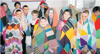  ?? ?? Children in an orphanage in Moldovawea­r blankets knitted in New Zealand.
A blanket knitted in strips during Operation Coverupwil­l be sent overseas.