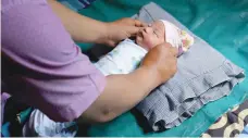  ?? — AFP ?? Abidah Asian Games, a newborn baby girl named as such after she was born hours before the games’ opening ceremony, is tended to at the family home in Palembang on Tuesday.