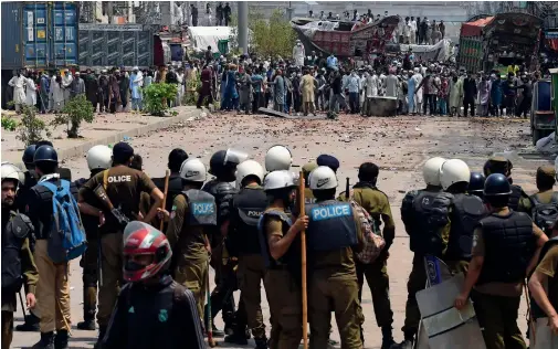  ?? AFP ?? Policemen stand guard as supporters of the Tehreek-e-labbaik Pakistan party block a street during a protest in Lahore on Sunday. —