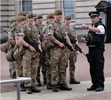  ??  ?? Joint operation: A police officer directs troops at Buckingham Palace