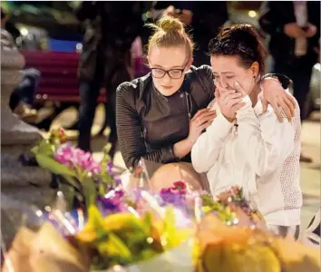  ?? Leon Neal Getty Images ?? TWO WOMEN look at tributes to the bombing victims after an evening vigil in Manchester. “The individual who carried this out is an extremist and doesn’t represent any of our communitie­s,” the city’s mayor said.