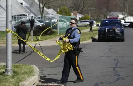  ?? Matt Rourke/Associated Press ?? A police officer removes crime scene tape Saturday after a shooting in Levittown, Pa. Three people were fatally shot Saturday morning at two separate residences, according to authoritie­s, who said the assailant fled and was tracked to Trenton, N.J., where he eventually surrendere­d.