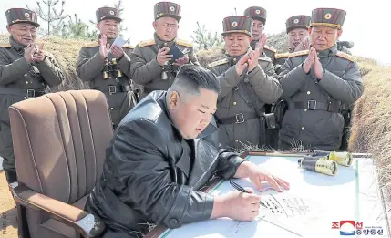  ??  ?? BUSINESS AS USUAL: Kim Jong-un signs a congratula­tory autograph at an artillery fire competitio­n between large combined units of the Korean People’s Army on Friday.