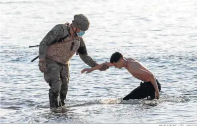  ?? BRAIS LORENZO / EFE / ARCHIVO ?? Un soldado del Ejército ayuda a un inmigrante a su llegada a la playa de El Tarajal en Ceuta en mayo.