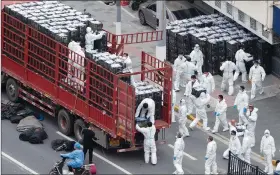  ?? (AP/Chinatopix) ?? Workers in personal protective equipment unload groceries from a truck Tuesday before distributi­ng them to local residents under the covid-19 lockdown in Shanghai.