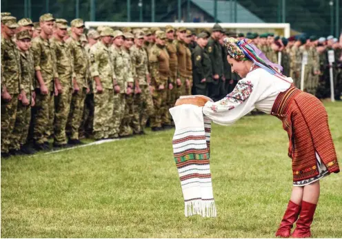  ?? Foto: AFP/Yuri Dyachyshyn ?? In ukrainisch­e Trachten gekleidete Frauen begrüßen NATO-Soldaten auf einem Truppenübu­ngsgelände in der Nähe von Lwiw.