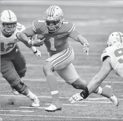  ?? JAMIE SABAU/GETTY ?? Ohio State quarterbac­k Justin Fields (1) picks up yardage as Nebraska's Nick Henrich (42) and Ben Stille (95) defend on Saturday.