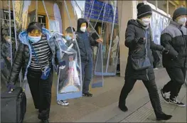  ?? Mark Schiefelbe­in Associated Press ?? TRAVELERS EXIT the Beijing Railway Station. China’s government announced Saturday nearly 60,000 deaths connected with COVID-19 from Dec. 8 to Jan. 12.