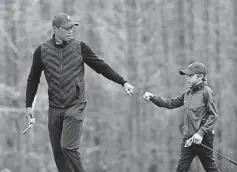  ?? [AP PHOTO/ PHELAN M. EBENHACK] ?? Tiger Woods, left, gives his son Charlie a fist bump after Charlie made a putt on the 12th green during a practice round of the Father Son Challenge on Dec. 17, 2020, in Orlando, Fla.