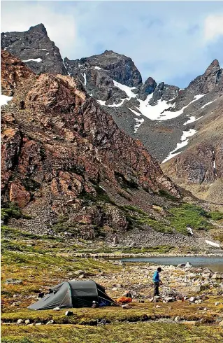  ?? ANDREW BAIN ?? A trekker in camp on the shores of Laguna de los Dientes at the foot of the Dientes de Navarino mountains.