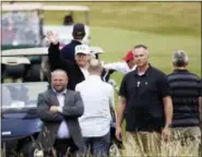  ?? PETER MORRISON — THE ASSOCIATED PRESS ?? U.S. President Donald Trump waves to protesters while he plays golf at Turnberry golf club, Scotland, Saturday. Trump is spending the weekend at his sea-side Trump Turnberry golf resort in Scotland, where aides had said he would be busy preparing for his Monday summit in Helsinki, Finland.