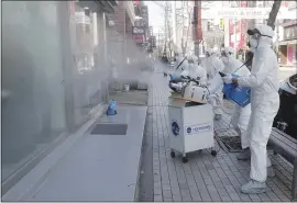  ?? AHN YOUNG-JOON — THE ASSOCIATED PRESS ?? Workers wearing protective gear spray disinfecta­nt as a precaution against the coronaviru­s at a shopping street in Seoul, South Korea, Thursday. South Korea is the hardest-hit country outside China, where the virus originated.