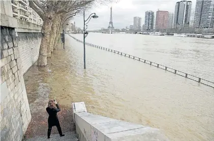  ?? EFE ?? La Torre Eiffel. Una mujer fotografía el mayor símbolo de París, mientras el agua del Sena desborda.