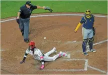  ?? AP PHOTO/AARON DOSTER ?? Umpire Brian O’Nora, top left, signals safe as the Cincinnati Reds’ Elly De La Cruz yells while sliding across home plate after hitting an inside-the-park home run against the visiting Milwaukee Brewers this past Monday.