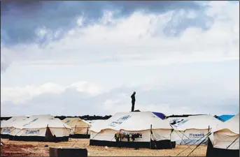  ??  ?? In this Jan 9, 2013 file photo, a Syrian refugee stands on top of a water tank at Zaatari refugee camp, near the Syrian border in Mafraq, Jordan. A Jordanian official says a nighttime riot at a Syrian refugee camp close to the Jordan-Syria border has left two Syrian refugees and a Jordanian policeman hurt. Anmar Hmoud, says the rioting in Zaatari camp started late Sunday and stretched into the early hours of Monday. (AP)