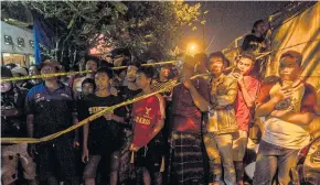  ??  ?? People gather in front of an apartment building after an explosion in Sidoarjo, East Java, on May 13. The Indonesian government is now caring for three children who were orphaned after their parents and eldest sibling were killed when the bombs they...