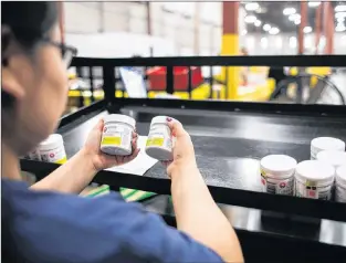  ?? CP PHOTO ?? A worker examines cannabis products at the Ontario Cannabis Store distributi­on centre in an undated handout photo.