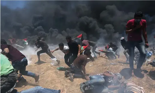  ??  ?? PALESTINIA­N RIOTERS run from IDF fire and tear gas at the border in the southern Gaza Strip on Monday.