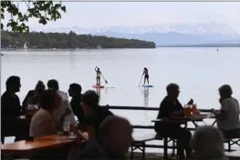  ?? MATTHIAS SCHRADER — THE ASSOCIATED PRESS ?? People enjoy the sunny weather on the re-opening day of beer gardens, following the lifting of measures to avoid the spread of the coronaviru­s at lake ‘Ammersee’ in front of the alps in Inning, Germany.