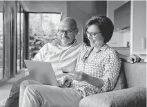  ?? RAINER BERG Westend61 / Getty ?? A couple makes a payment with a credit card on their laptop at home.