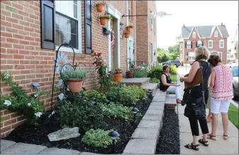  ??  ?? People stand outside a Boyertown residence and view the planted area as they judge it for the Home Garden Contest.