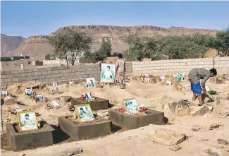  ?? AFPPIX ?? ... Yemeni children stand by the graves of schoolboys at a cemetery in the Huthi rebels’ stronghold province of Saada on Tuesday. The boys were killed while on a bus that was hit by a Saudi-led coalition air strike on the Dahyan market last month.