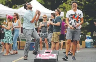  ?? Seth McConnell, The Denver Post ?? Nick Miano, left, reacts after Dan Scardigli landed a bag in the hole during a corn hole game during Sesh Fest on Aug. 5 in Denver.