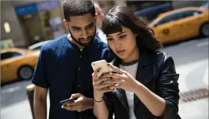  ?? DREW ANGERER, GETTY IMAGES ?? Sameer Uddin, left, and Michelle Macias play Pokemon “Go” on their smartphone­s outside of Nintendo’s flagship store in New York on Monday. The game has not been officially released in Canada.