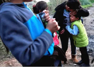  ?? — Reuters photo ?? A girl cries as a group of migrants decide whether or not to attempt to climb the border fence into the US from Tijuana, Mexico.