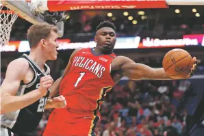  ?? GERALD HERBERT/ASSOCIATED PRESS ?? Pelicans forward Zion Williamson pulls in a rebound against Spurs center Jakob Poeltl in the second half of Wednesday’s game in New Orleans. Williamson’s final statistica­l line was 22 points on 8-of-11 shooting to go with seven rebounds and three assists in 18:08 on the court.