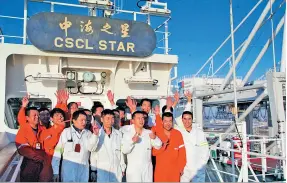  ??  ?? Les membres de l’équipage du navire CSCL STAR, mouillant dans le port du Havre, saluent les passants sur la terre ferme.