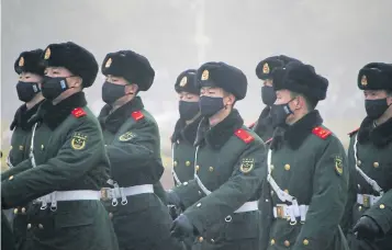  ?? REUTERS ?? Paramilita­ry police officers wearing masks patrol during smog at Tiananmen Square after a red alert was issued for heavy air pollution in Beijing, China, on December 20.