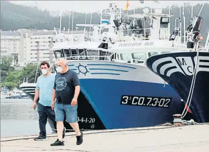  ?? ELISEO TRIGO / EFE ?? Dos homes passejant ahir pel port de Burela, a la comarca d’A Mariña (Lugo)