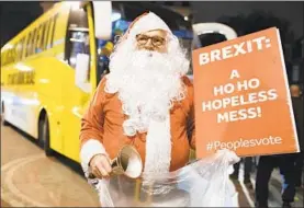  ?? LEON NEAL/GETTY ?? An anti-Brexit protester dressed as Santa Claus makes his feelings clear Monday outside Parliament in London. Parliament’s vote on the deal with the EU was postponed.