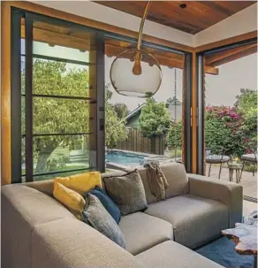  ??  ?? THE ELEVATED ADU made largely with recycled redwood has thermal sliding door panels that allow a view to the backyard and pool. The bathroom features energysavi­ng devices: notouch hand washing, a 1-gallon flush toilet and a low-f low rain showerhead.