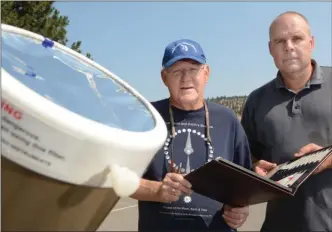  ?? GARY NYLANDER/The Daily Courier ?? Jim Tisdale, left, and Terry Bridges, both members of the Royal Astronomic­al Society of Canada, Okanagan Centre, hold a book containing data on exactly when today’s partial solar eclipse will occur in Kelowna. Tisdale and Bridges will have their...