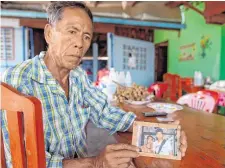  ??  ?? Jai Sutham holds a photo of rescued grandson Prachak Sutham