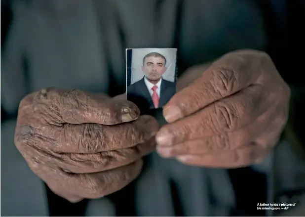  ?? — AP ?? A father holds a picture of his missing son.