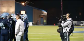  ?? (Arkansas Democrat-Gazette/Justin Cunningham) ?? Steve Raum (right), a producer for the digital sports network Overtime, films Pulaski Academy Coach Kevin Kelley talking to sophomore linebacker Harrison Lane (far left) during a 2019 playoff game. The footage is being used for a series focusing on the team called To the House, which is being shown on Overtime’s YouTube profile, Overtime SZN.