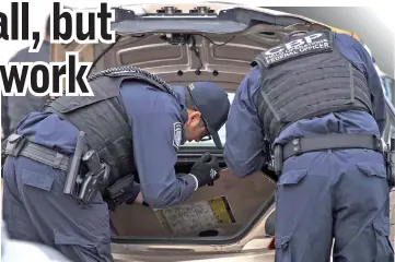  ??  ?? Two US Customs and Border Protection officers, working in anti-terrorism contraband enforcemen­t, search the trunk of a car in the preprimary inspection area at the San Ysidro.