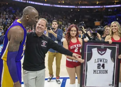  ?? Mitchell Leff/Getty Images ?? Kobe Bryant of the Los Angeles Lakers and his Lower Merion High School coach Gregg Downer share a moment prior to a game against the Philadelph­ia 76ers on Dec. 1, 2015. Downer is still Lower Merion’s coach and has guided the team to a 25-1 record this season.