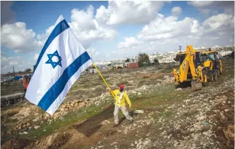  ?? ( Yonatan Sindel/ Flash90) ?? A MAN with an Israeli flag walks in the Givat Hamatos neighborho­od of Jerusalem on Monday.