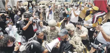  ?? AP / Ringo Chiu ?? SOLIDARIOS. Miembros de la Guardia Nacional se unieron ayer a los manifestan­tes para hacer una oración en una calle de Hollywood en la ciudad de Los Ángeles.