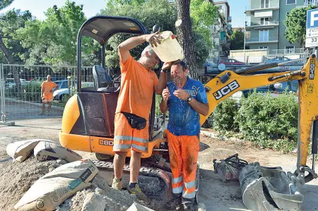  ??  ?? Gavettone Operai in un cantiere stradale a Verona si rinfrescan­o con improvvisa­te docce per evitare l’esauriment­o da calore