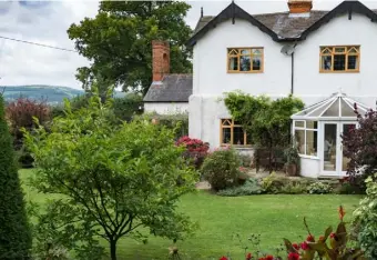  ?? The kitchen garden, with four raised beds planted with asparagus, lettuce, herbs and rhubarb; Clematis
‘Princess Diana’; the nearly-500-year-old farmhouse is set against the Shropshire hills; purple bell vine
OPPOSITE
Tucked away behind trees, shrubs a ?? THIS PAGE, CLOCKWISE FROM TOP LEFT