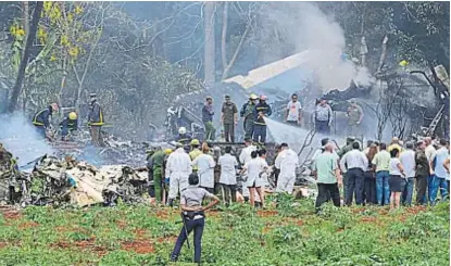  ?? (AP) ?? Restos en el campo. Bomberos apagan las últimas llamas del avión caído en La Habana.