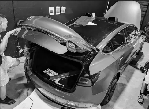  ?? SCOTT JACOBS / COURTESY OF EDMUNDS VIA AP ?? A car wrap is installed on a Tesla Model 3. The job to apply this metallic light blue vinyl cost about $3,700 at a shop in Southern California. This included parts, labor and an optional ceramic coating for added durability.
